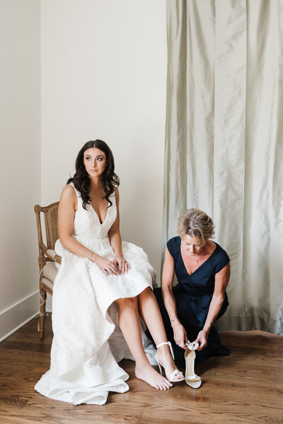 mother of the bride helping put shoes on