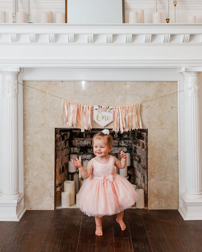 One year old baby in front of a fireplace with a birthday sign