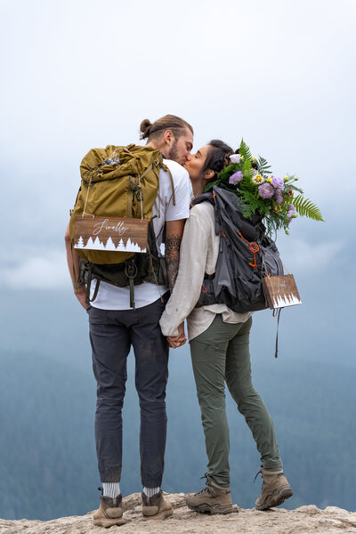 A couple kissing with hiking backpacks on