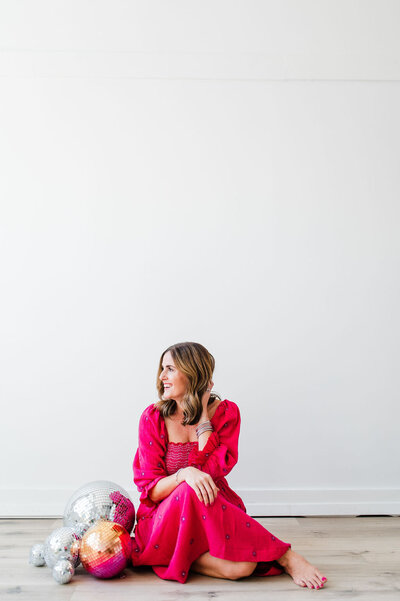 woman in pink dress sitting on floor with disco balls