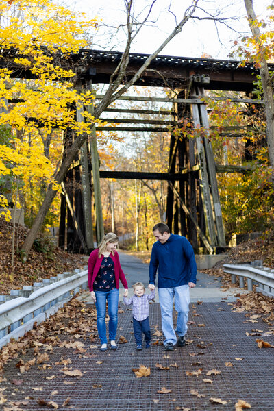 Family holding hands and walking on bridge at Ironstone Park in Boyertown
