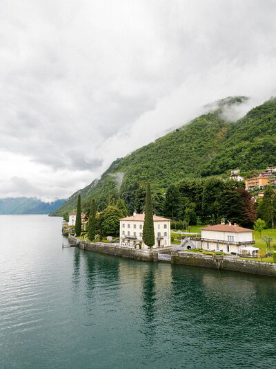 large estate on water with mountains in the background
