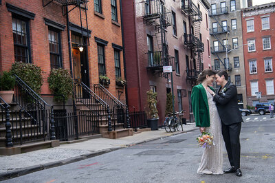 A wedding couple standing on a city street with their heads together 