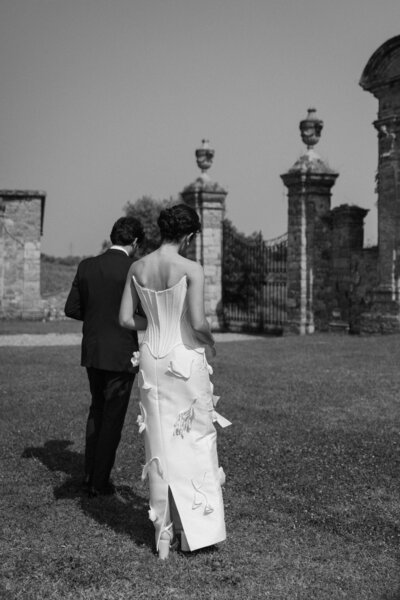 Two people walking across a lawn after getting married 