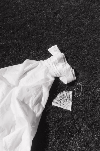 Wedding dress on the ground surrounded by pearls and a lace fan outside of Tayvin Gardens Wedding Venue in Bowling Green, Kentucky.