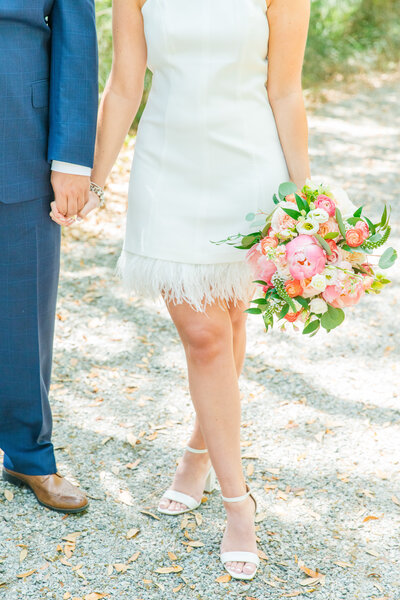 detail of short white elopement dress with weather trim and colorful peony bouquet