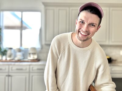 A friendly realtor ready to help you buy a home in Cave Creek. He is standing in a kitchen in a ball cap.