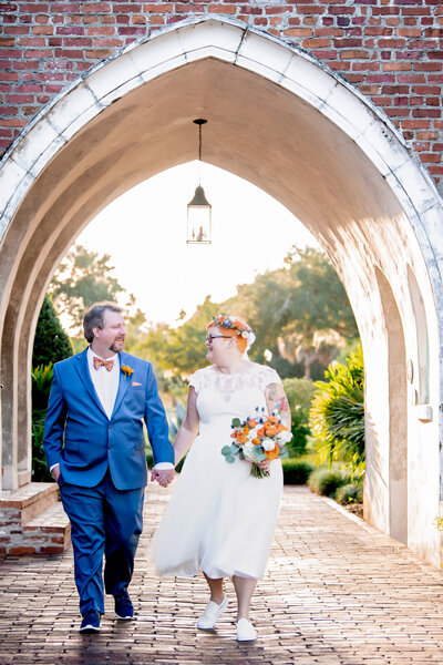couple walking holding hand under arch 