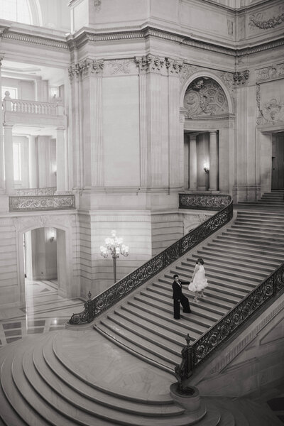 Bride and groom walking down a grand marble staircase inside an ornate building, captured by a Washington wedding photographer.