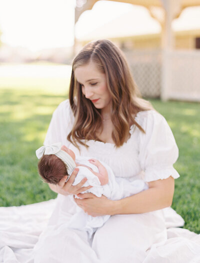 young woman in white dress holds newborn baby in tulsa newborn photos
