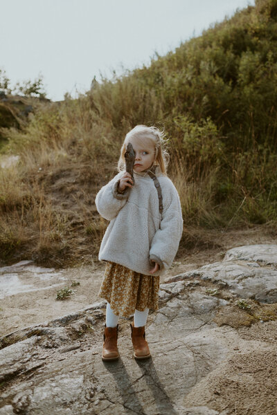 4 year old child holding a piece of dry bark in front of her eye  in Suomenlinna in  Finland