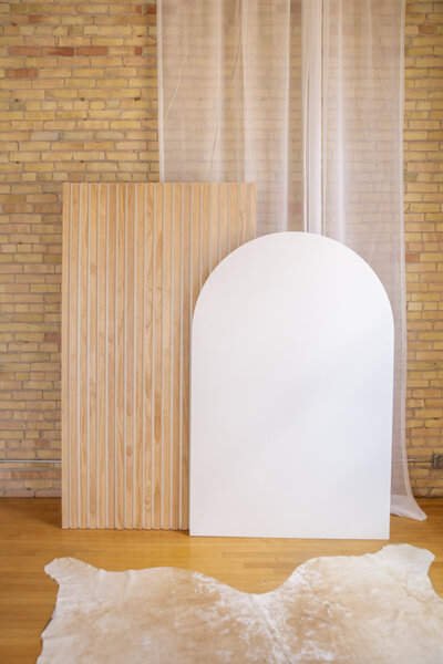 A seven foot tall wooden slat wall and a six foot tall white arch.