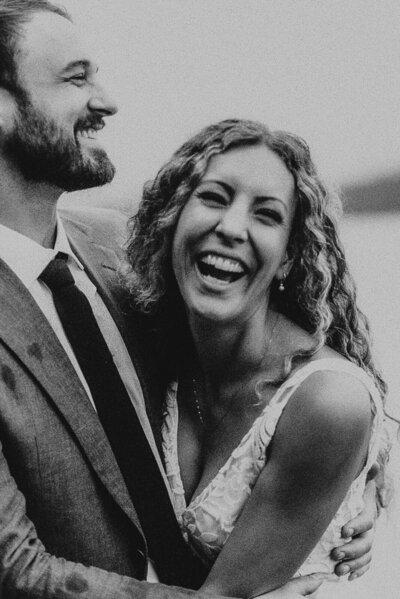 bride and groom laughing on dock on lake