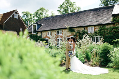 bride-kissing-groom-at-luxury-wedding-at-bury-court-barn-in-surrey-by-leslie-choucard-photography