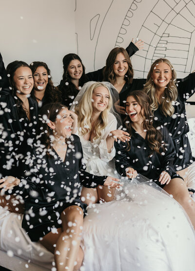 bride and bridesmaids throwing confetti on bed
