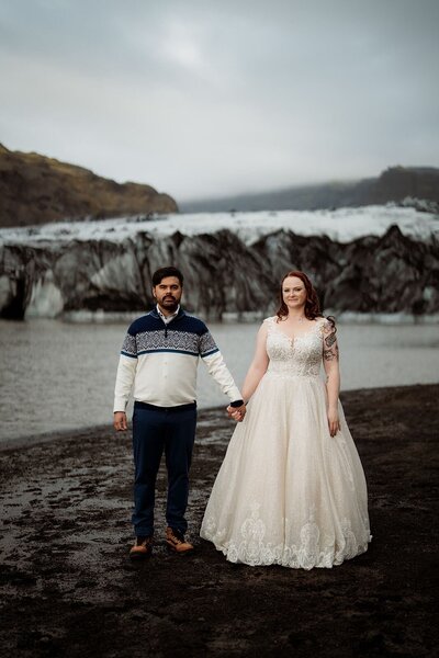 Bride & groom holding hands on the shore of a glacial lake in Iceland!