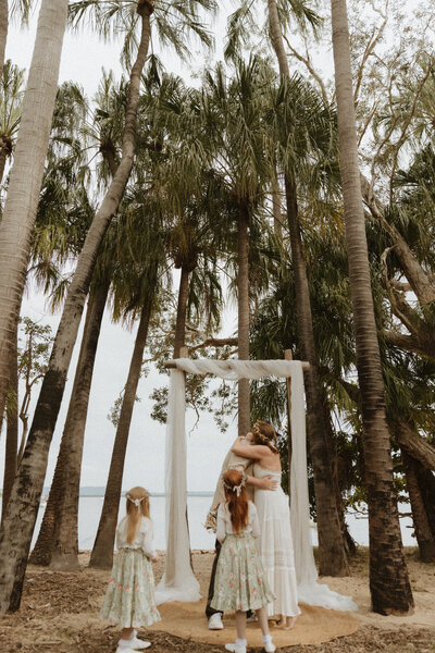 Wedding down at 1770. Husband and wife kissing, their two kids standing in front of them