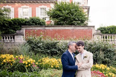 Two husbands stand next to each other hugging on their wedding day. 