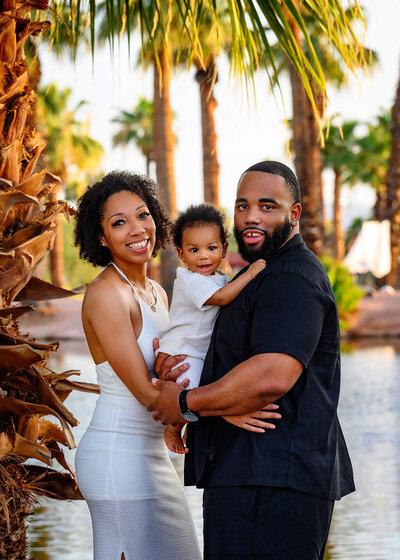 mom and dad with a smiling baby boy in an embrace at the Papago Park in Phoenix