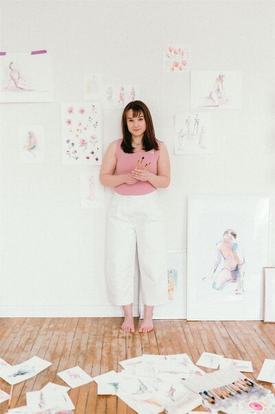 Stephanie Anne, Quebec-based live wedding sketch artist, showcasing her custom illustration work in a bright studio setting
