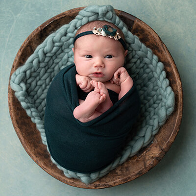 Newborn baby wrapped in teal, toes peeking out