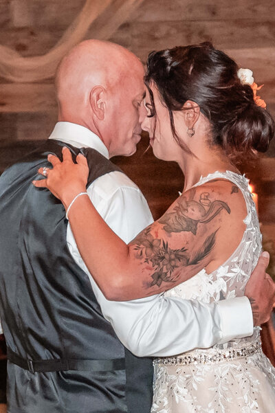A bride and groom share a romantic first dance, surrounded by soft lighting and joyful guests at their wedding celebration. - photo by Jamie Simmons