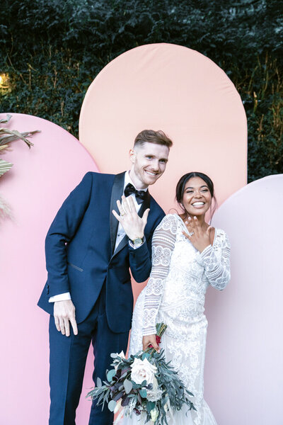bride and groom posing against a backdrop, during their wedding party entertainment using the Selfie pod party photo booth rental or hire