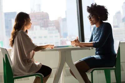 Two young women discuss partnership in business pitch meeting