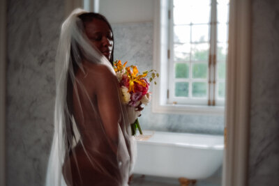 woman with a bride's veil and bouquet in front of a window