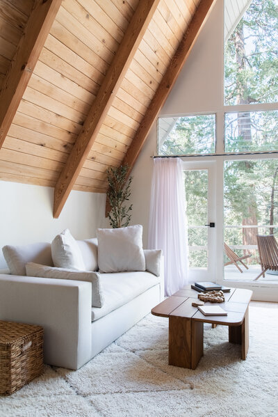 White bedroom with a window view of pine trees