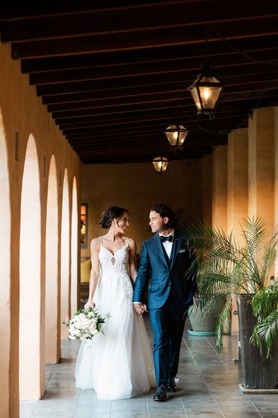 Bride and groom walking down the corridor at Royal Palms wedding venue looking at each other smiling