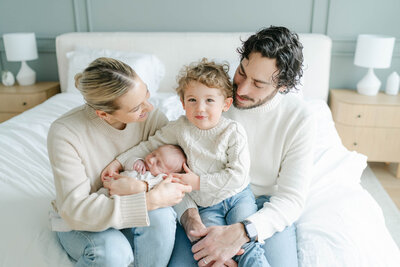 family of five cuddles on their bed with their newborn baby during a newborn session with AnneMarie Hamant