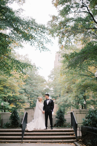 bride and groom standing on steps in park during outdoor bridals