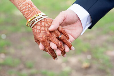 Henna tattooed bride holds hands with her groom on their wedding day