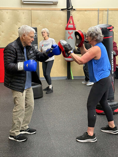 Lori and a warrior practice non-contact boxing in the Warriors Gym during a Parkinson's exercise class.