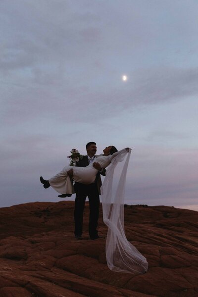 bride and groom under the moon in snow canyon state park