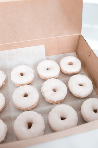 white glazed donuts in a pale cardboard box surprise gift
