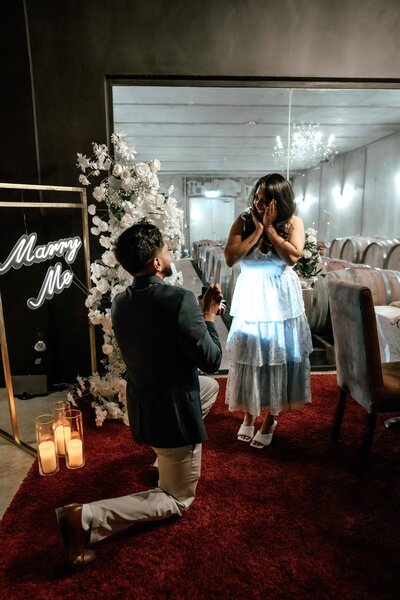 Groom proposing indoors with romantic floral and candlelit setup, photographed by Auckland proposal photographer Zanthe Vorsatz.