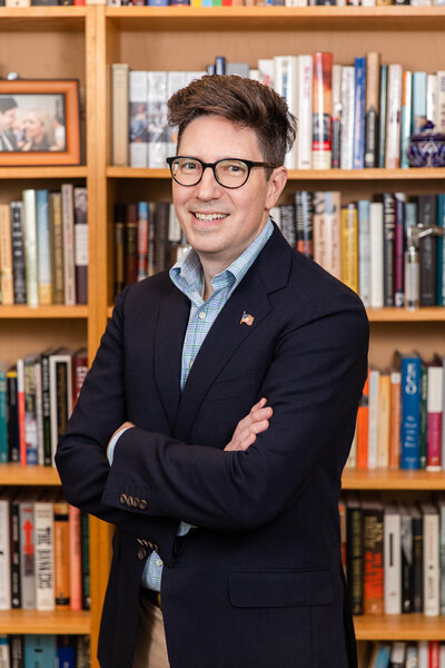 professional headshot of man standing in front bookshelves by laure photography
