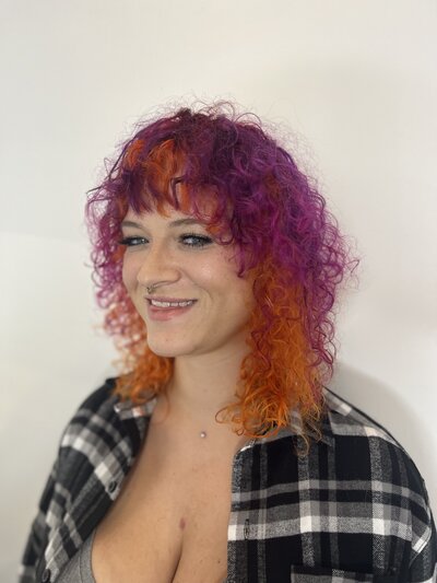 Image of client with hair that has been dyed vivid pink and orange.