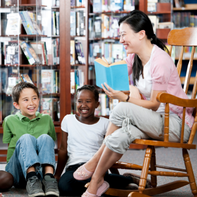 Woman holding a book and reading to children