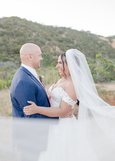 bride and groom facing each other and smiling. 
