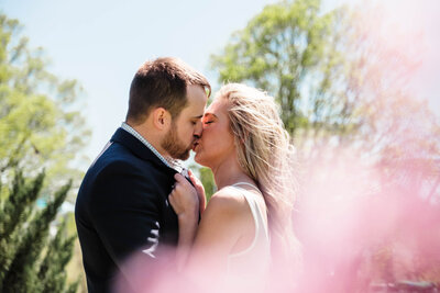 A joyful engaged couple walks hand in hand through a scenic park in Nashville, TN, with the city skyline in the background. The bride-to-be laughs as the wind tousles her hair, capturing a candid and romantic moment. This engagement session highlights the artistry of Alabama wedding photography in a vibrant urban setting.