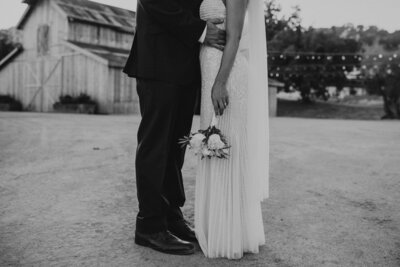 A bride and groom standing close together at [venue name].