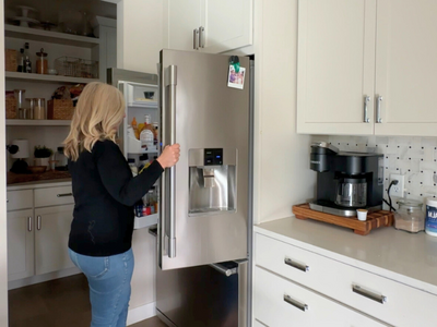 Smartphone displaying the Supper Club meal planning app with weekly menus, next to fresh produce spilling from a grocery bag.
