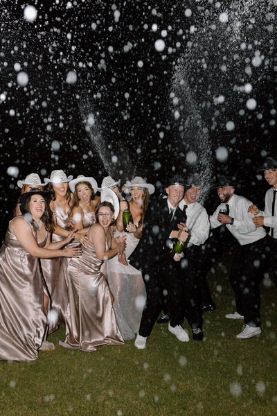 A bridal party doing a champagne pop together.