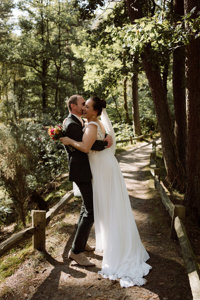 Wedding fotoshoot in het bos - Bruidegom tilt de bruid op. 