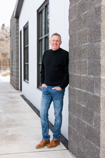 Branding headshot of a client standing outside in black attire, smiling at the camera.