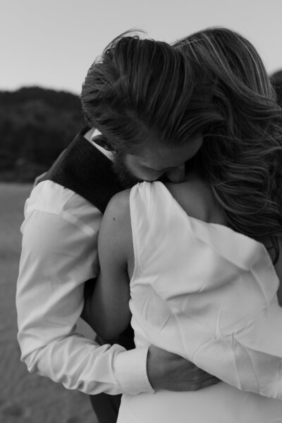 man kissing woman's shoulder taken by san francisco wedding photographer