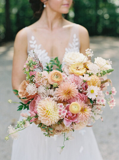 Fall bridal bouquet with lush autumnal colors of mauve, dusty pink, cream, white, peach, taupe, and green. Florals of dahlias, roses, clematis, lisianthus, and natural greenery. Fall wedding in Raleigh, NC. Design by Rosemary and Finch Floral Design in Nashville, TN.